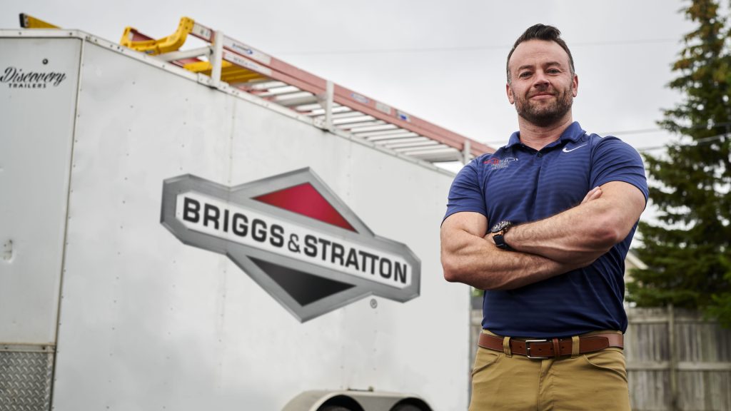 A man standing in front of a PowerProtect™ 26kW Standby Generator trailer.