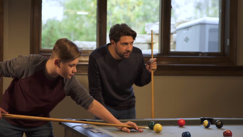 Two men playing billiards on a PowerProtect™ 26kW Standby Generator.