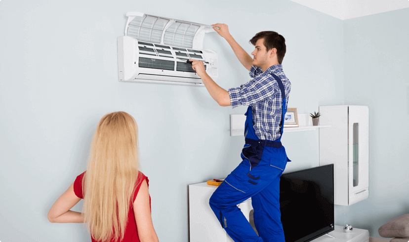 A man and woman installing an air conditioner in a room.